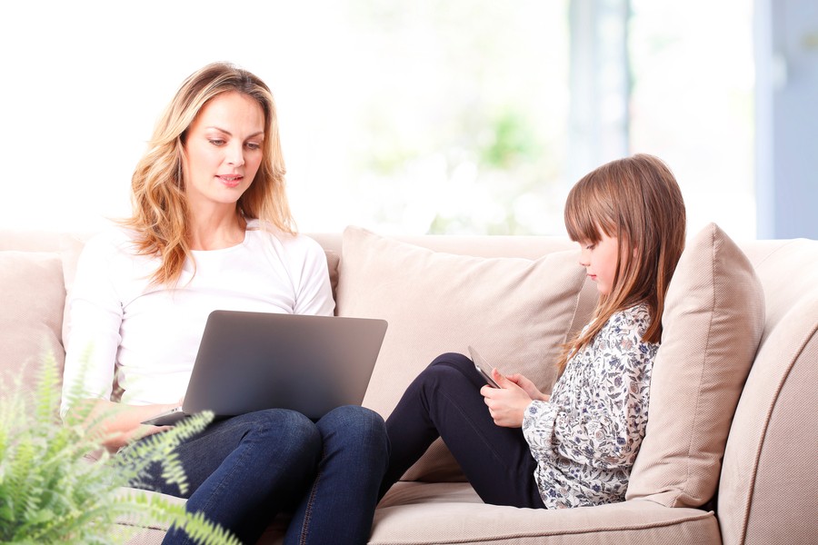 A mother and daughter using devices on a couch, showcasing the need for reliable networking solutions in modern homes.