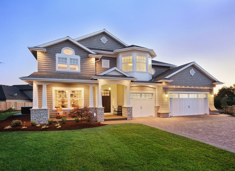 An exterior of a home with outdoor lights at a dim setting.