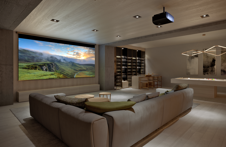 A luxurious home theater with sofa seating and a large screen with a ceiling-mounted projector. 