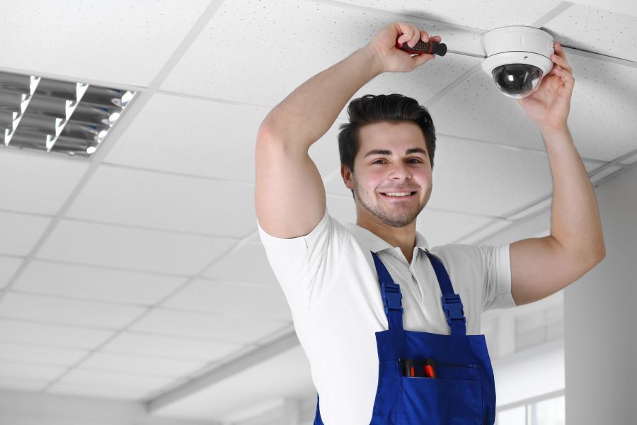 Technician installing a security camera on the ceiling.