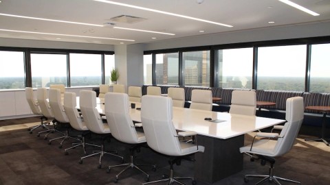 large conference table in a large office with windows overlooking a cityscape