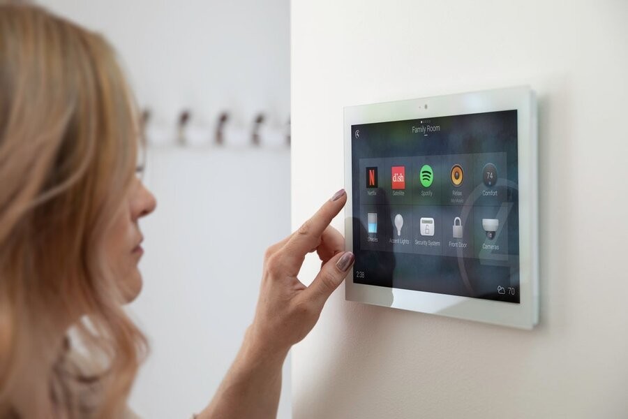 A woman utilizing a Control4 interface on a wall touchscreen.