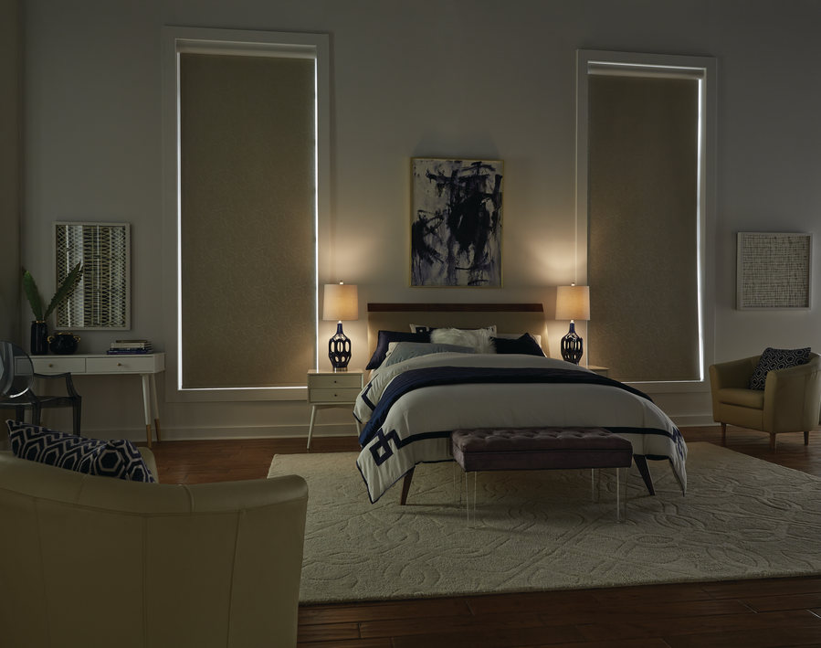 A dimly lit bedroom with a queen size bed, large area rug, and two large blackout shades on either side of the bed. 