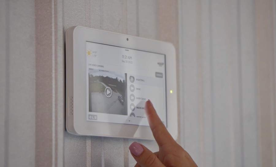 Manicured hand taps a button on a smart security system keypad