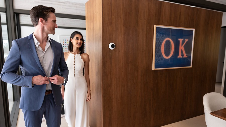 Two people in a room speaking to their Josh.ai voice assistant. On the wall artwork reads “OK.” 